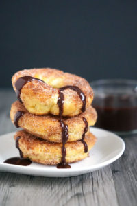 Stack of baked churros drizzled with chocolate sauce.