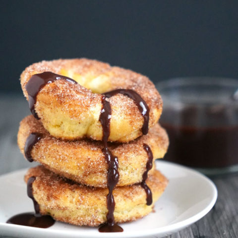 Stack of baked churros drizzled with chocolate sauce.