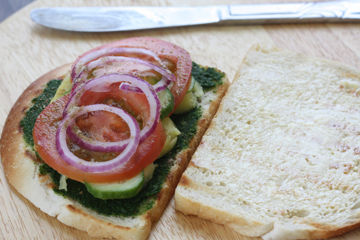 Open Bombay sandwich with chutney, potatoes, cucumbers, tomato, onions and masala.