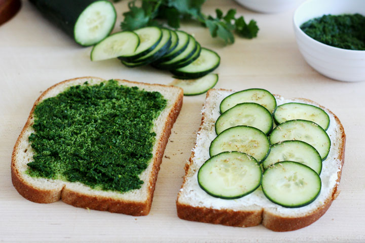 Bread slices with one showing cream cheese and cucumbers on top and the other spread with mint cilantro chutney.