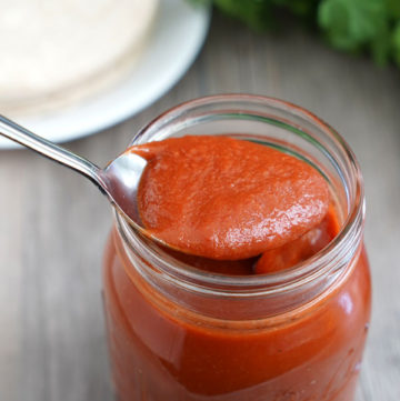 Enchilada sauce being spooned out of a jar.