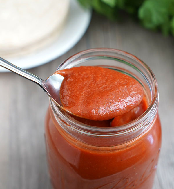 Enchilada sauce being spooned out of a jar.