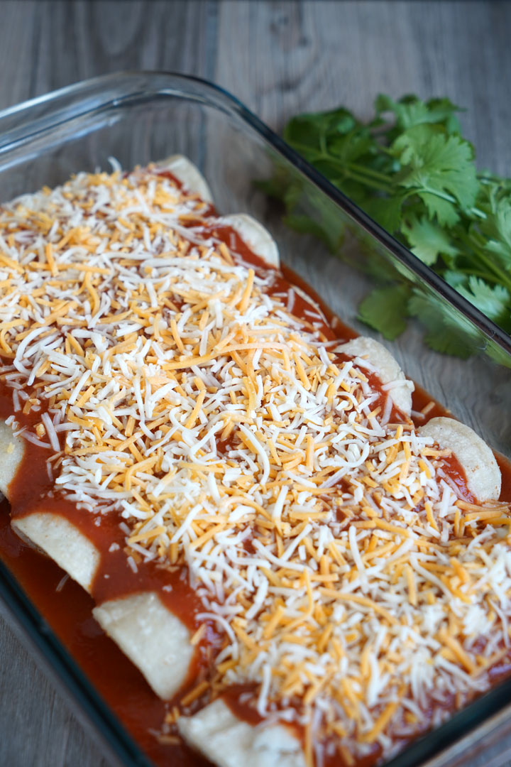 Uncooked cheese enchiladas in a tray.