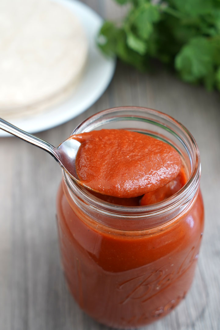 Enchilada sauce being spooned out of a jar.