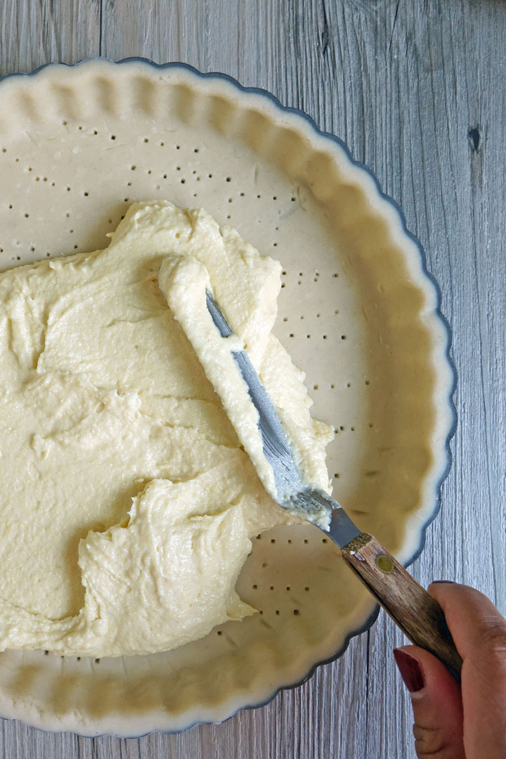 Frangipane being spread inside a tart shell.