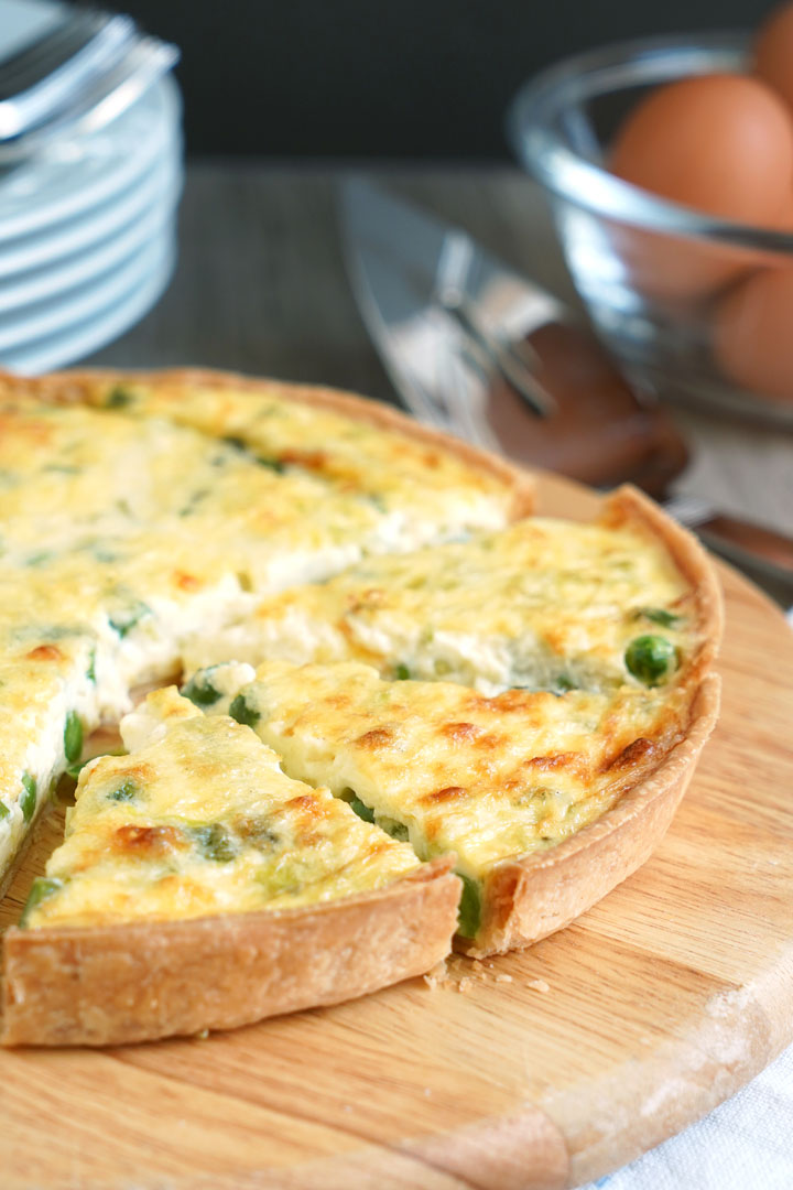 Vegetable quiche on a cutting board with pieces sliced. 