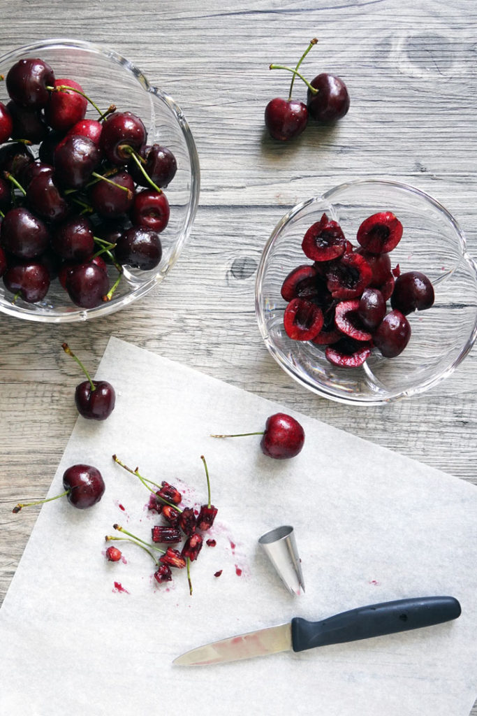 Cherries being pitted with a star shaped tip and cut in half with knife.
