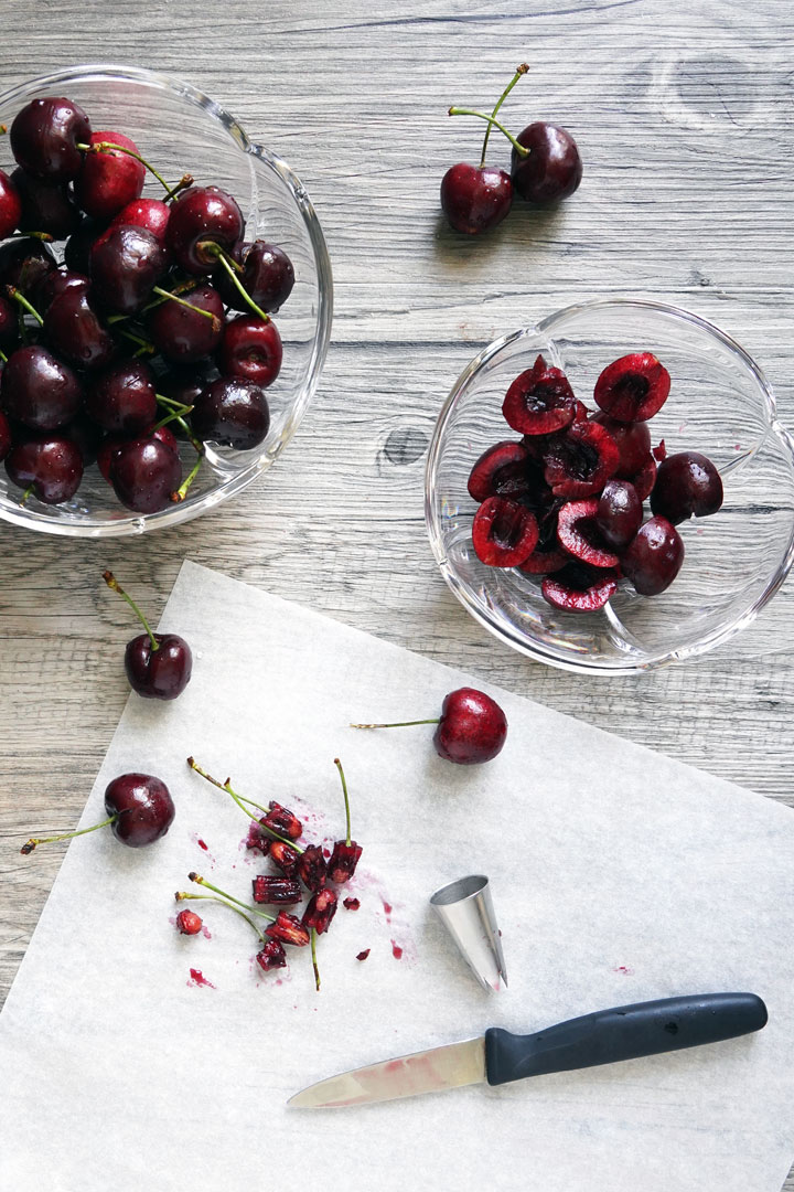 Cherries being pitted with a star shaped tip and cut in half with knife.