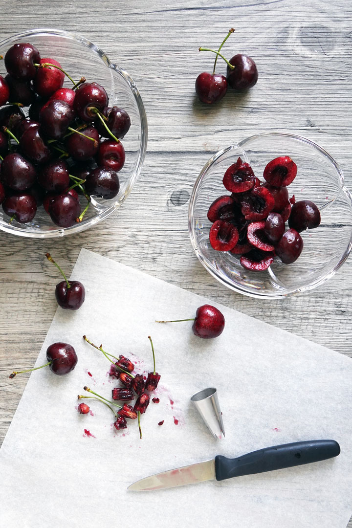 Cherries being pitted with a star shaped tip and cut in half with knife. 