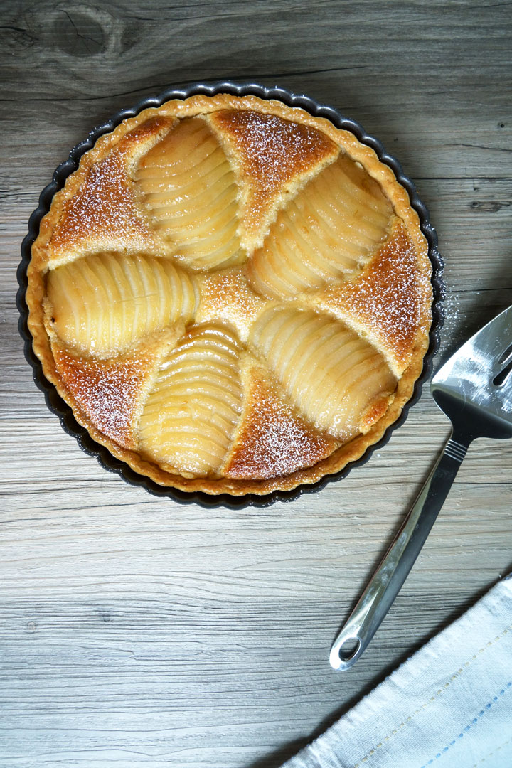 Overhead shot of pear and frangipane tart with spatula on side.