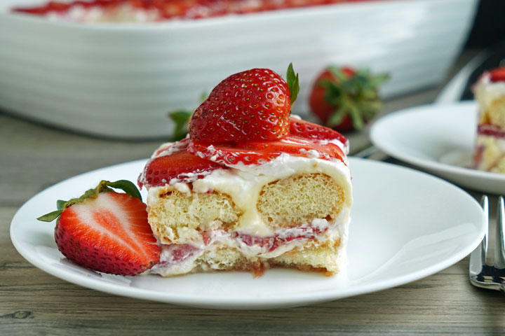 Slice of strawberry tiramisu on a white plate with fork. 