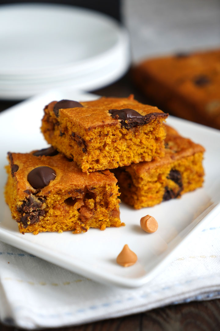 Three butterscotch pumpkin cake bars on a white plate over a napkin.