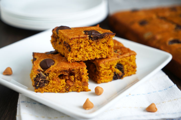 Three butterscotch pumpkin cake bars on a white plate over a napkin.