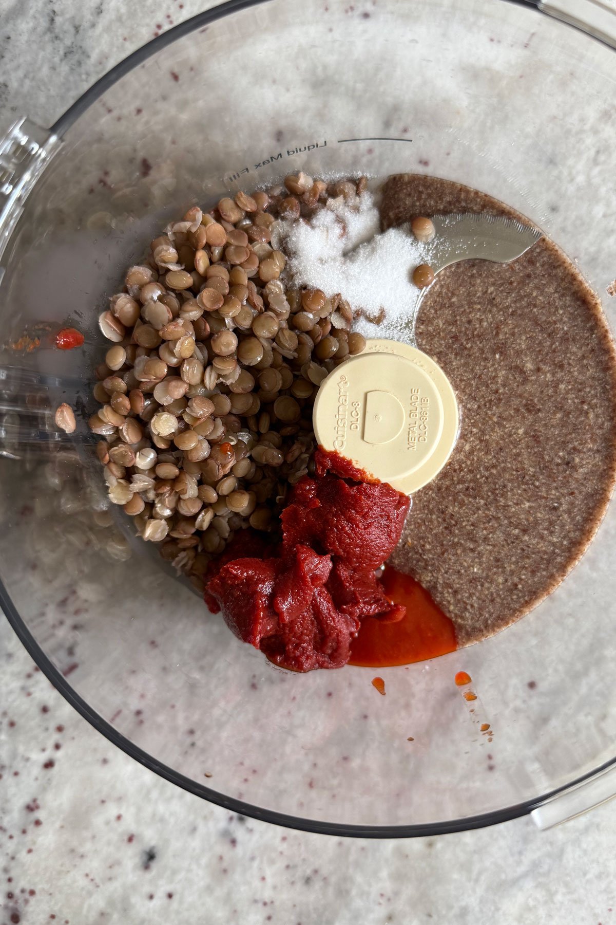 Mix of lentils, tomato paste, hots auce, salt and flax egg in food processor bowl.