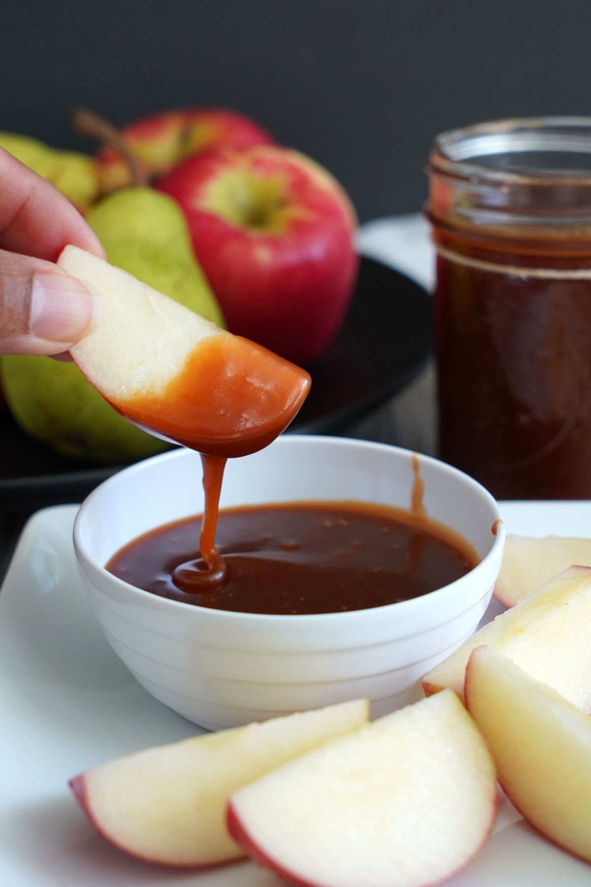 Apple slice being dipped into salted caramel sauce.