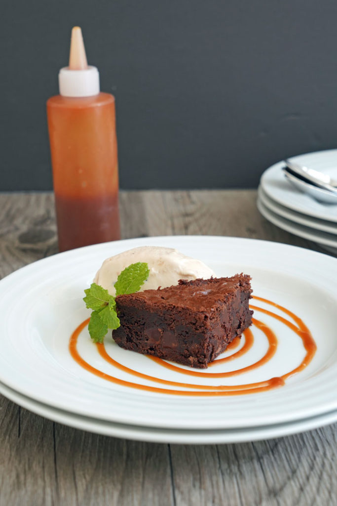 Plated brownie with ices cream using caramel sauce for decoration.