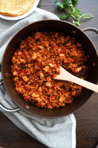 Cooked sofritas in a pan with wooden spoon.