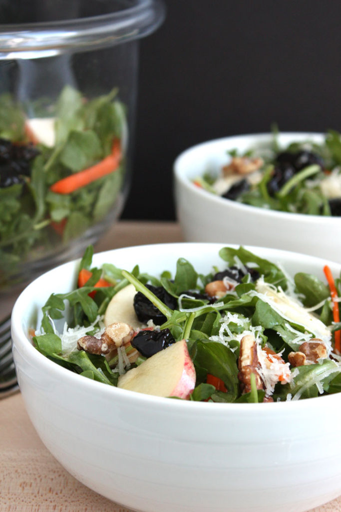 Fall arugula and apple salad in white bowl.