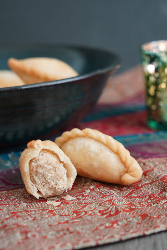 Fried Gujiya with bite taken to show inside filling.