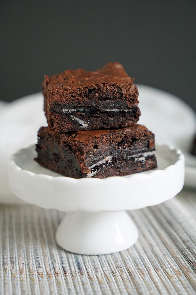 Oreo brownies stacked on a small white pedestal. 