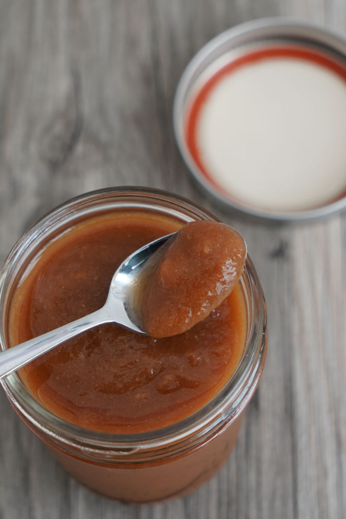 Tamarind paste being taken out of a jar with a spoon.