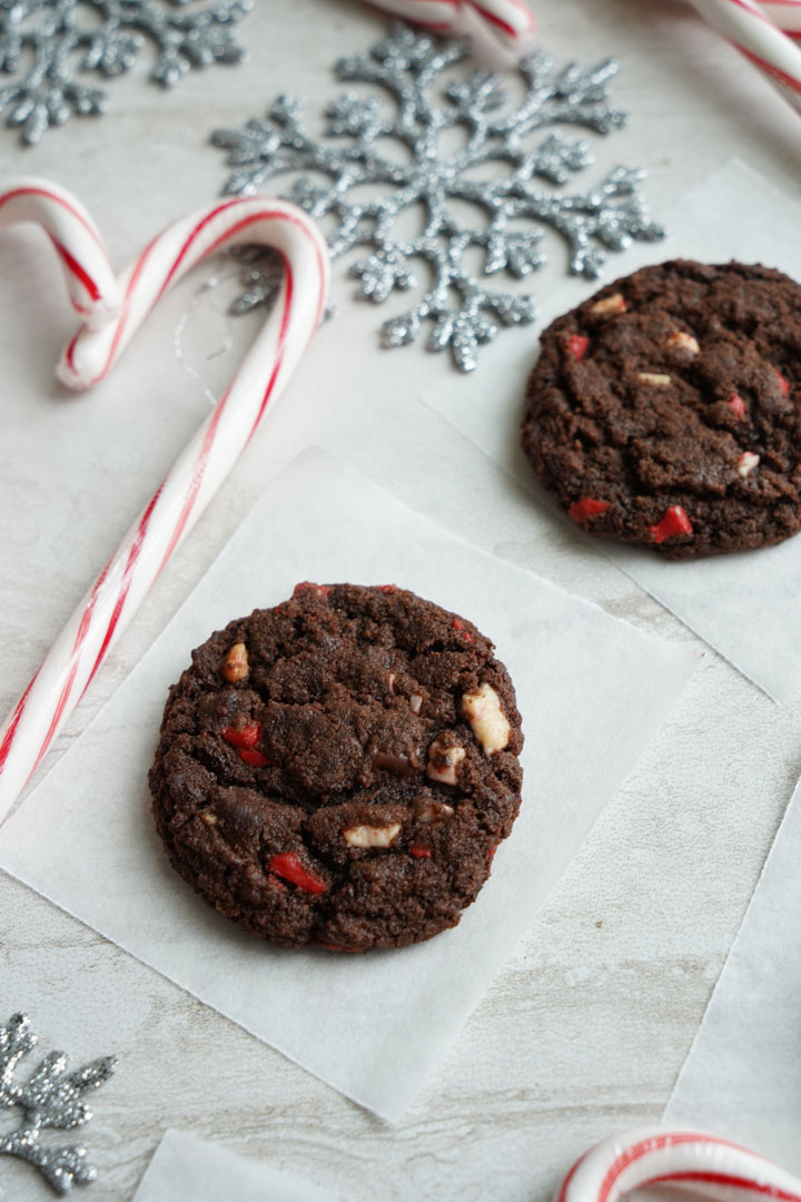 Chocolate peppermint chip cookies surrounded by candy canes and silver snowflakes.