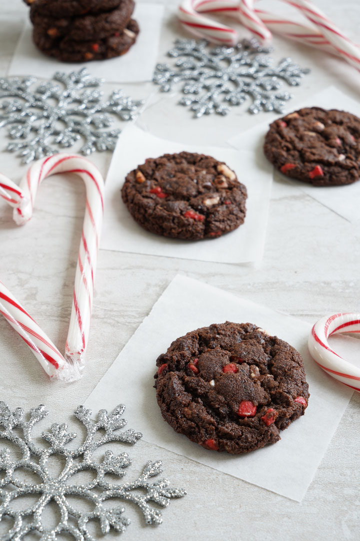 Chocolate peppermint chip cookies surrounded by candy canes and silver snowflakes.