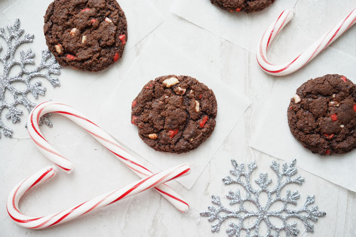 Chocolate peppermint chip cookies surrounded by candy canes and silver snowflakes.