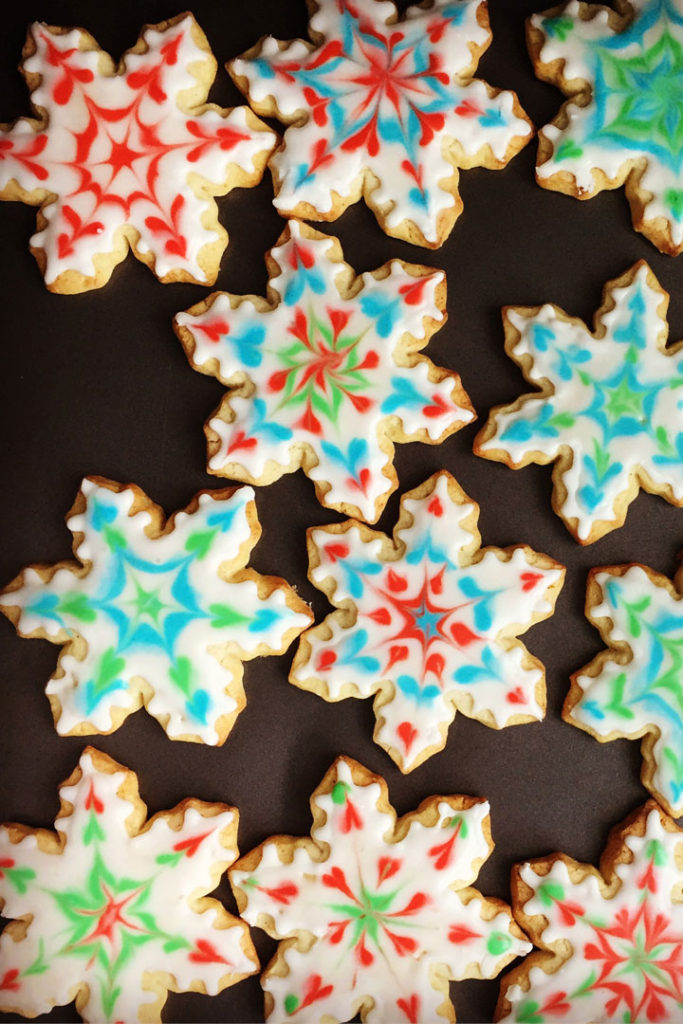 Snowflake shaped cookies decorated in various colors.