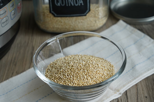 Dry uncooked quinoa in a clear glass bowl. 