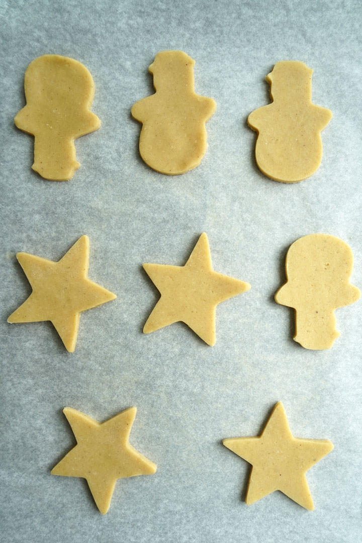 Raw cut sugar cookies on a cookie sheet.