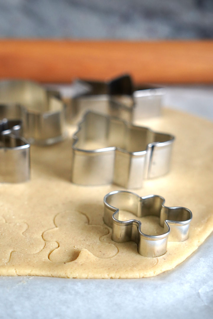 Cookies being cut out with metal cookie cutters. 