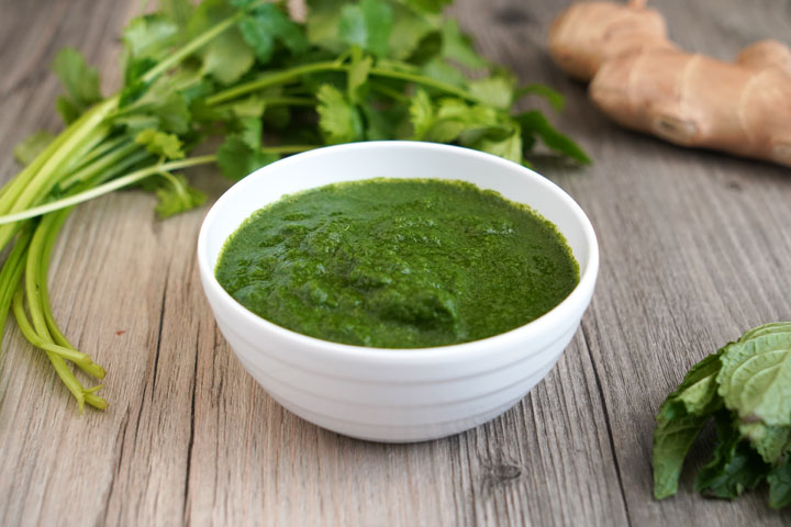 A bowl full of fresh cilantro and mint chutney.