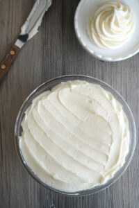 Cream cheese frosting in a clear glass bowl.