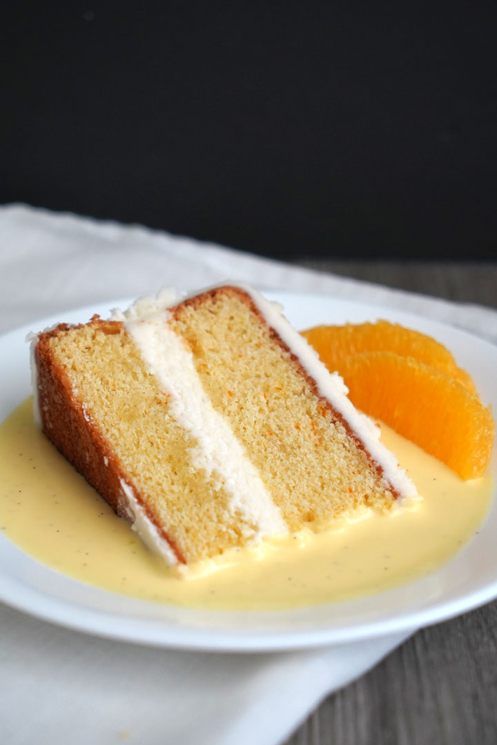 Slice of cake in a pool of custard sauce on a white plate. 