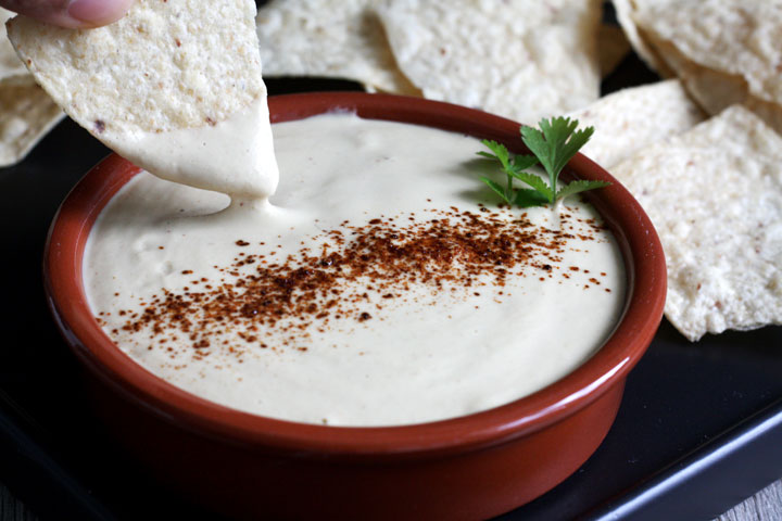 Chip being dipped into a vegan queso dip.