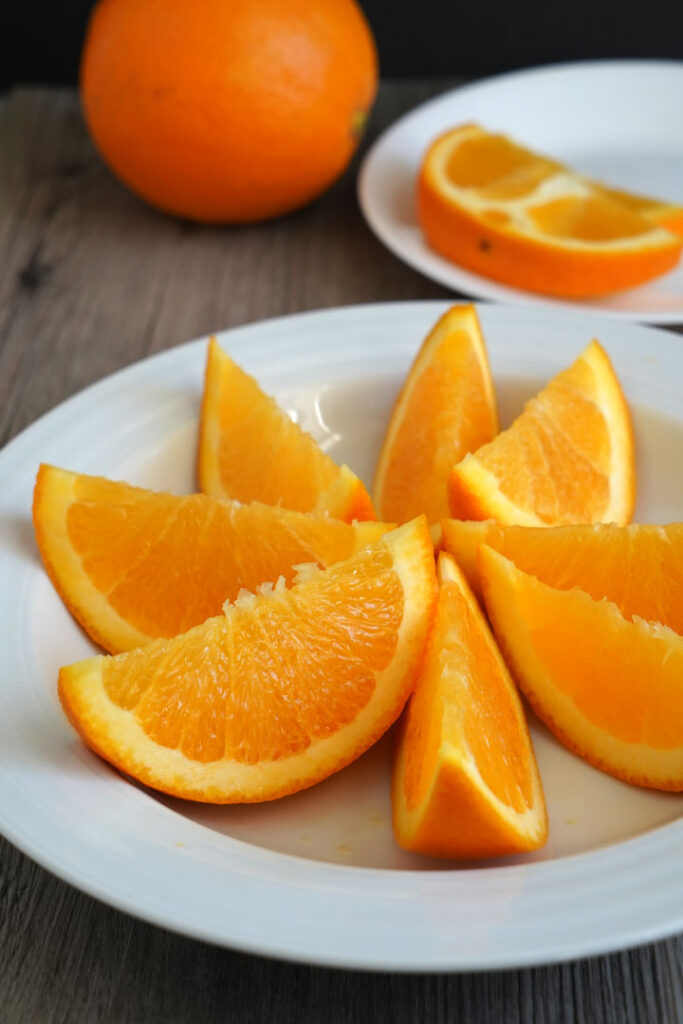 Sliced orange wedges in a white plate.