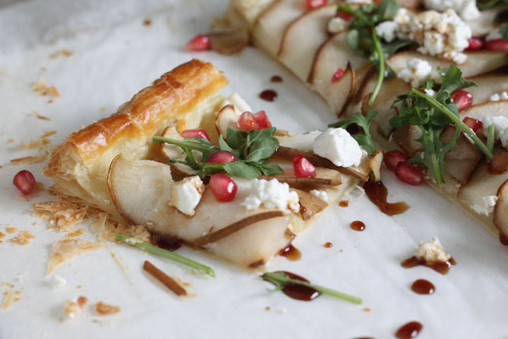 Slice of pear and goat cheese tart drizzled with balsamic on top of parchement paper.