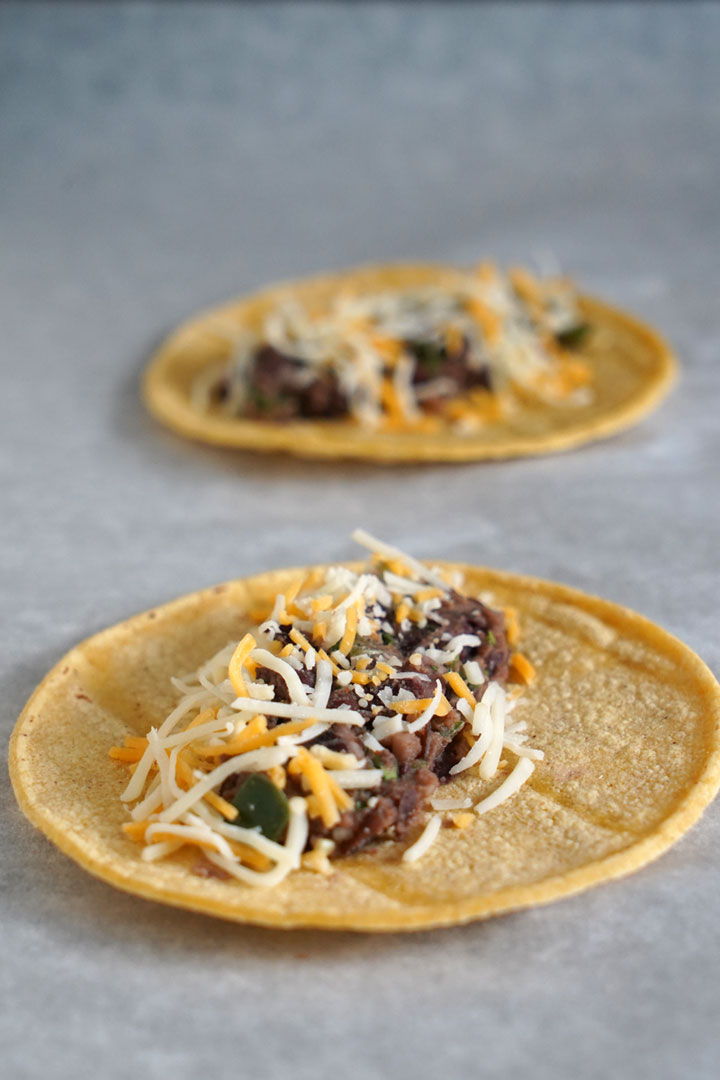 Bean and cheese mixture laid out on a corn tortilla.