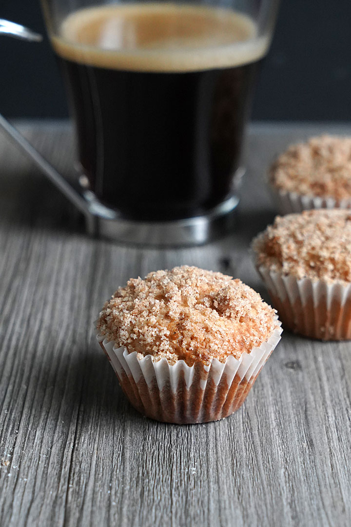 Mini coffee cake muffin with coffee mug in background. 