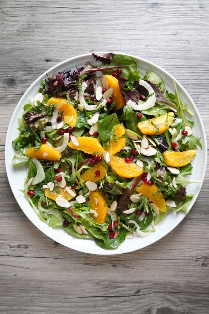 Overhead shot of platter  full of salad with carefully arranged orange slices.