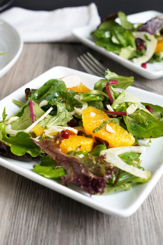 Close up of orange fennel salad on a white plate.