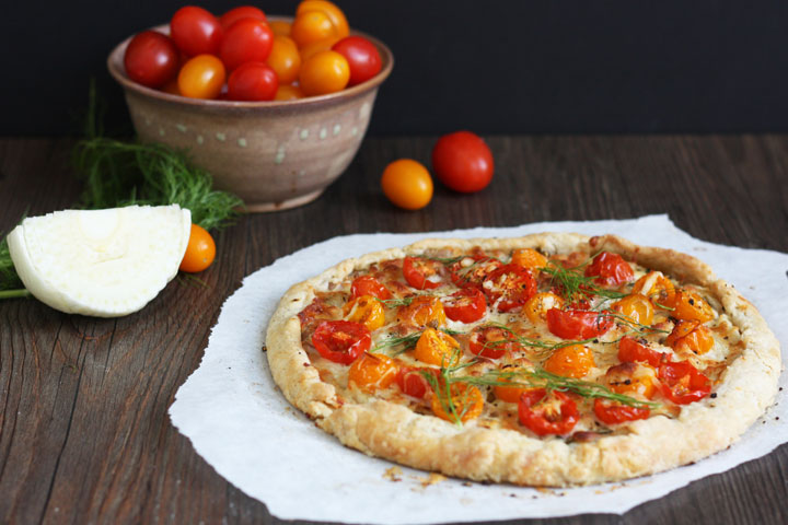 Whole tomato and fennel tart on wood board.