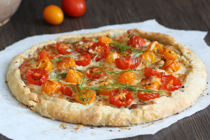 Whole tomato and fennel tart on wood board.