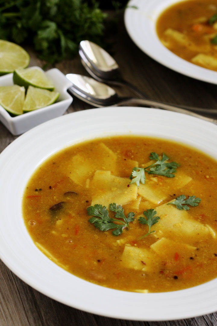 Dal dhokli in a white plate garnished with cilantro. Lime wedges on the side.