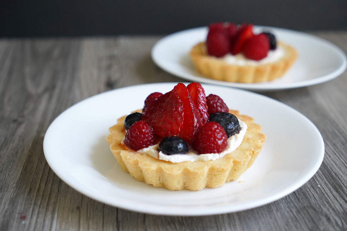 Two plates of berry fruit tarts.