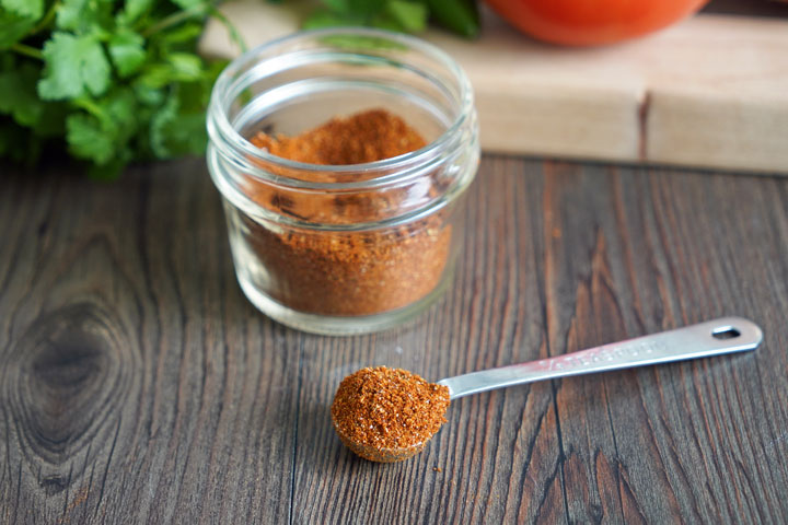 Spoonful of taco seasoning next to jar.