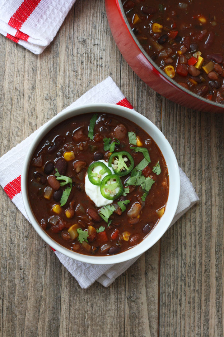 vegetarian chili in a white bowl next to red pot.