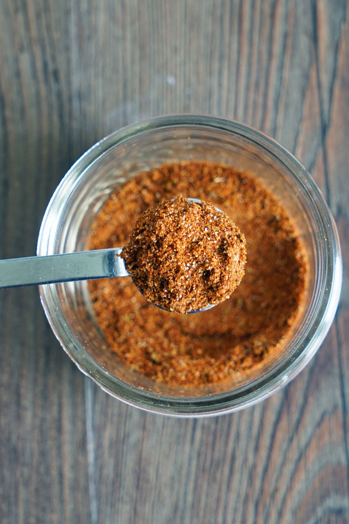 Taco seasoning in a jar with spoonful of seasoning.