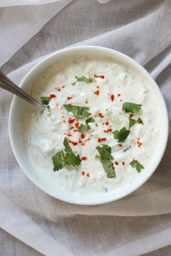 Cucumber raita in a white bowl.